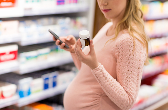 pregnant woman checking medication label