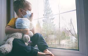 child on home quarantine looking out a window