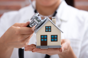 model of a house with a stethoscope applied to the roof