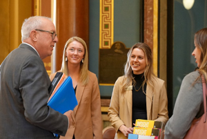University of Iowa Student Association for Rural Health members Hallie Vonk, Jenah McCarty, and Johanna Knutson visit with a state legislator during Public Health Day on the Hill at the Iowa State Capitol in February 2023.